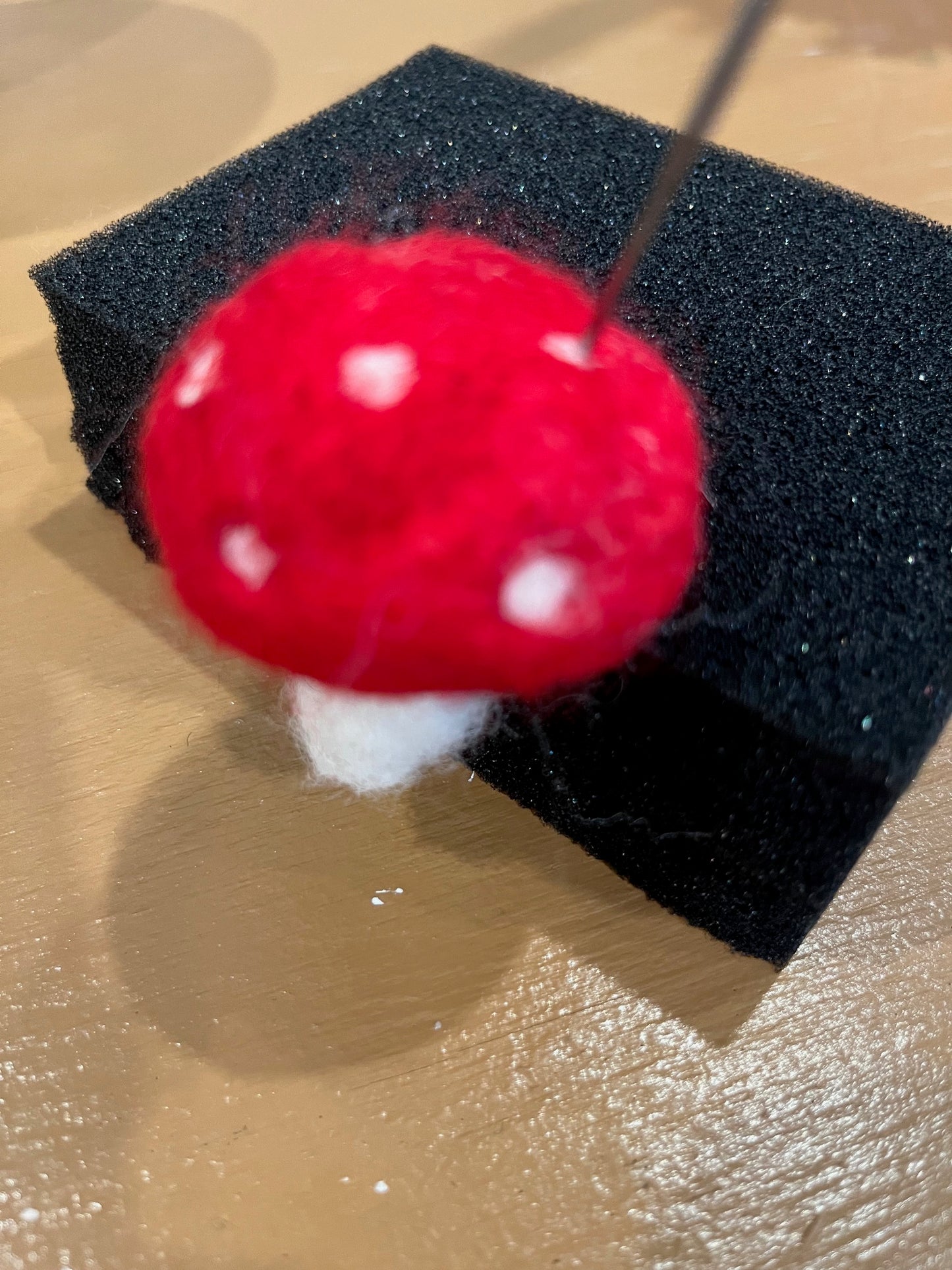 Needle felting white spots onto needle felted ivory and red wool mushroom example from Caron Design craft kit