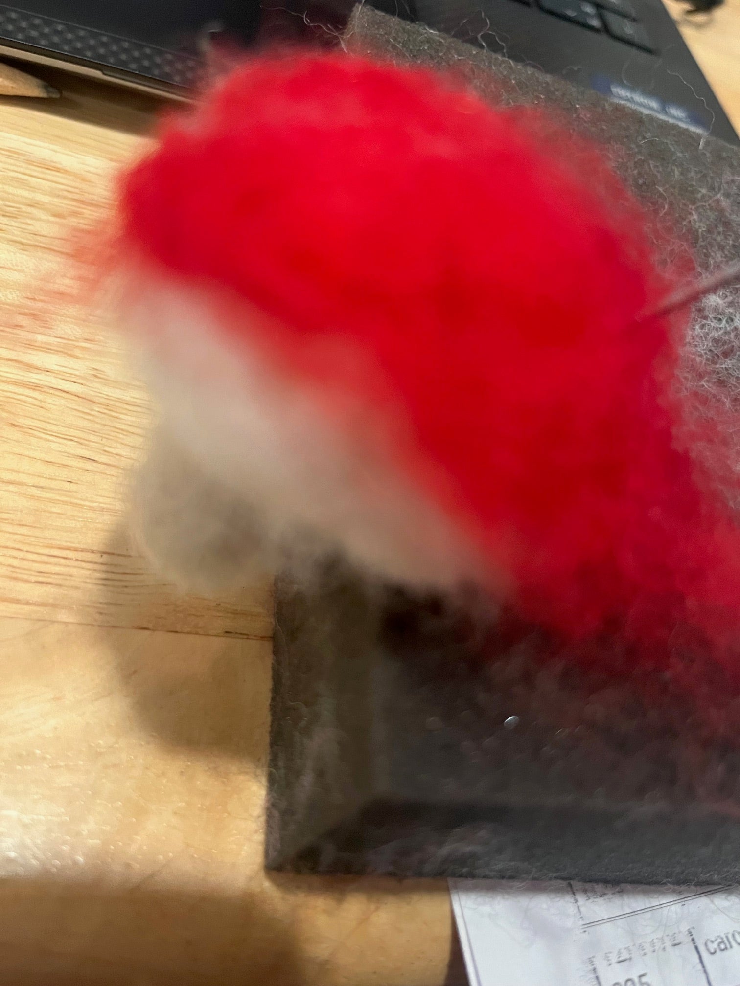Needle felting example on adding a layer of red wool roving on top of ivory roving. Finish project will be a felted mushroom.